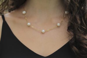 Cuello de mujer joven portando una gargantilla de perlas o collar corto de perlas.