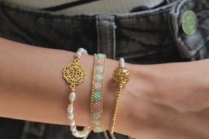 Mujer modelando pulseras de perlas y de chaquiras de colores